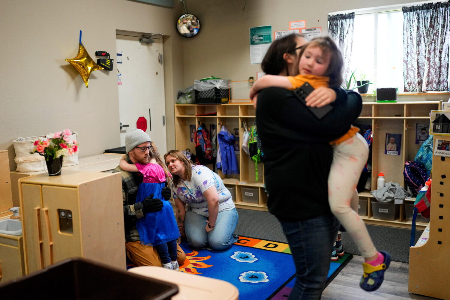 FILE - Olivia Starr clings to her father, Thaxter Hall, as Associate Educator Jessica Clark works t...