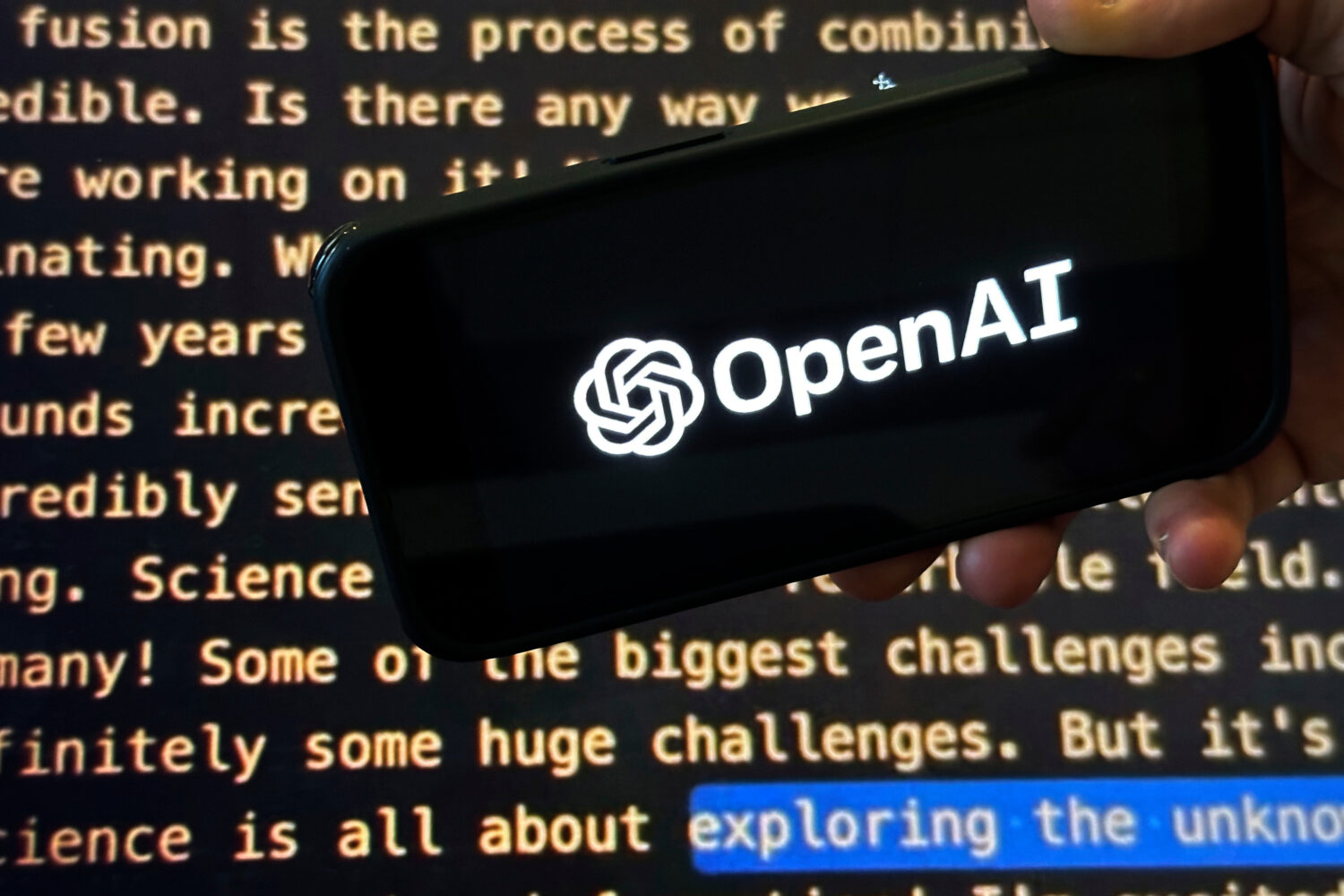 FILE - The OpenAI logo appears on a mobile phone in front of a screen showing part of the company w...