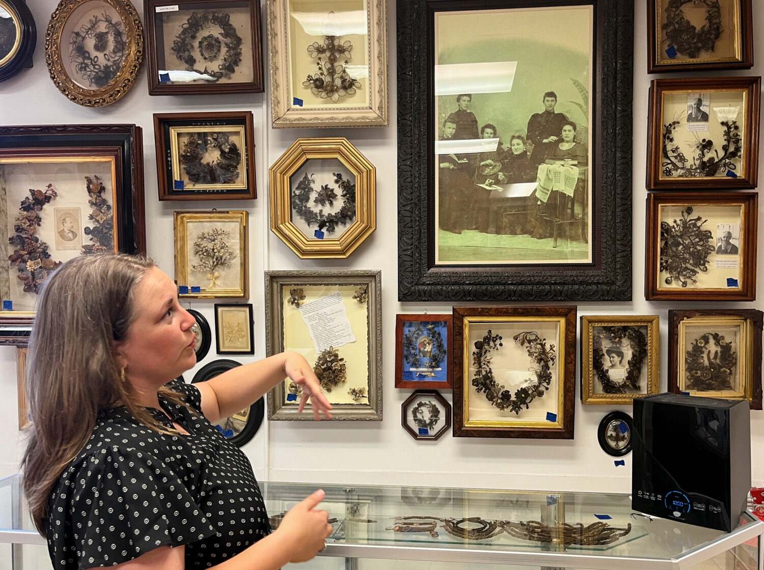 Lindsay Evans gestures to a historic photo of Victorian-era women weaving human hair into art, duri...