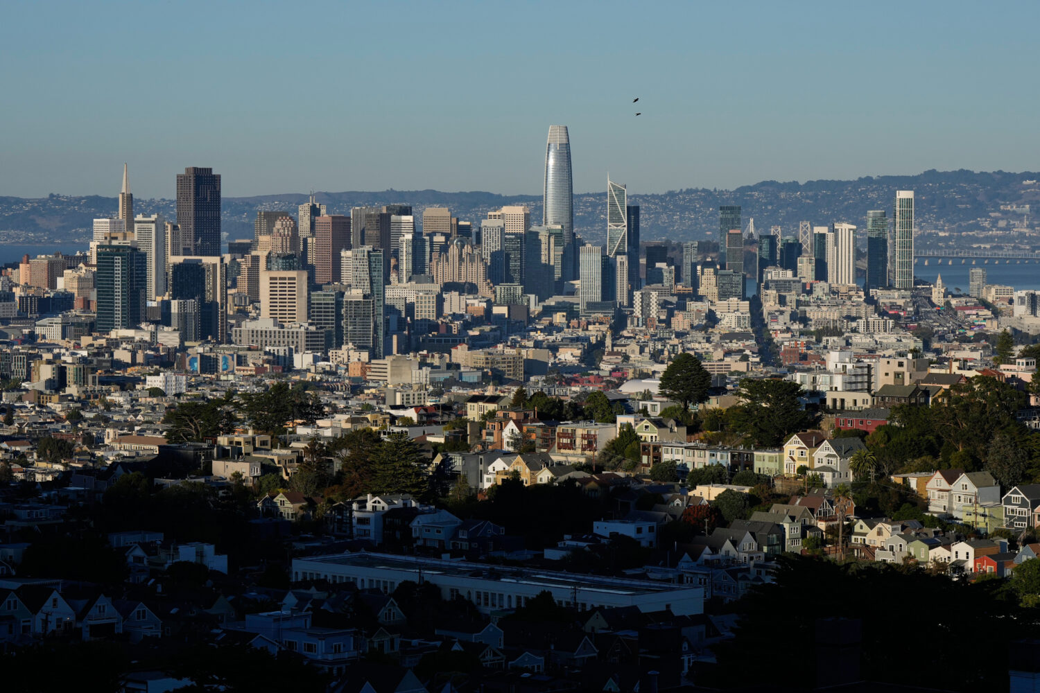Homes are illuminated by sunlight as the San Francisco skyline is seen in the background, Friday, O...